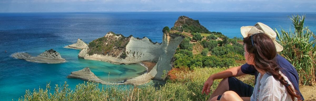 A couple on a mountain overlooking the ocean in Corfu, Greece on a sunny day.