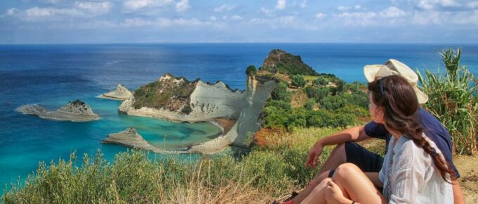 A couple on a mountain overlooking the ocean in Corfu, Greece on a sunny day.