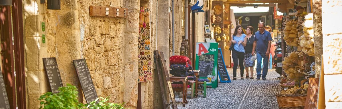 Tourists walking at the cobblestone street of old Rhodes town, Greece.