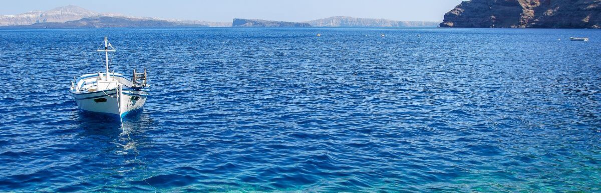 Santorini, Greek Island beach with a small boat on a sunny day.