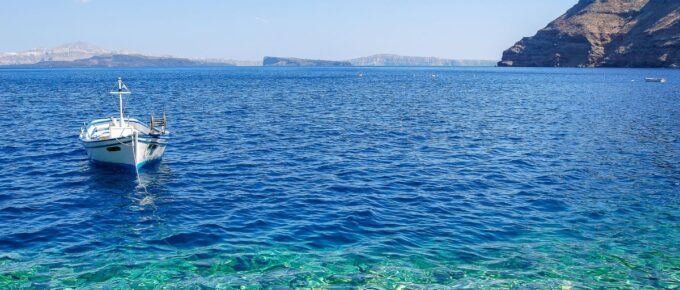 Santorini, Greek Island beach with a small boat on a sunny day.