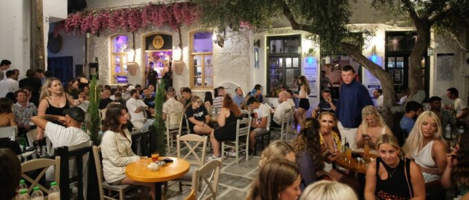 Young tourists surrounded by bars, enjoying drinks and cocktails at the popular square in Ios Greece at night.