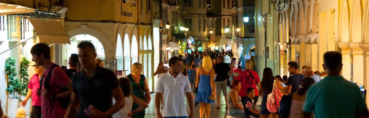 Tourists walk at night in Corfu island, Greece.