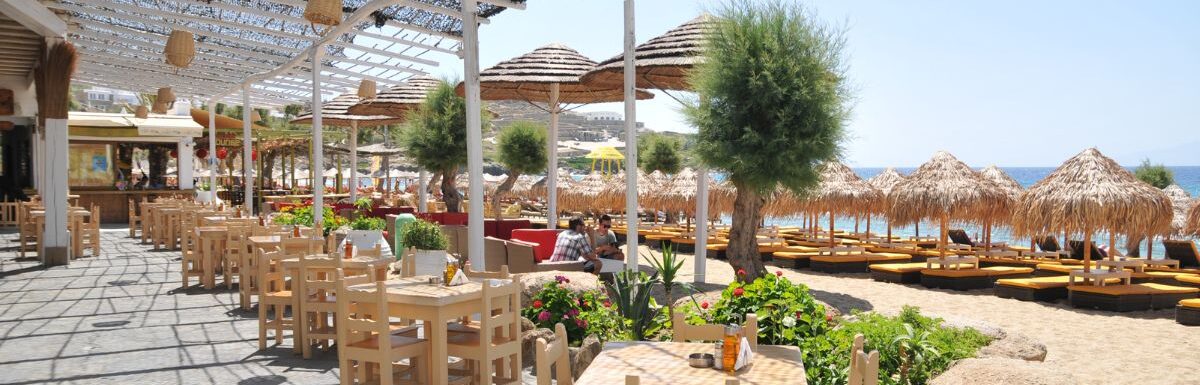 People are sitting at the cafe along Paradise Beach, Mykonos, Greece.