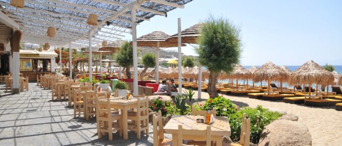 People are sitting at the cafe along Paradise Beach, Mykonos, Greece.