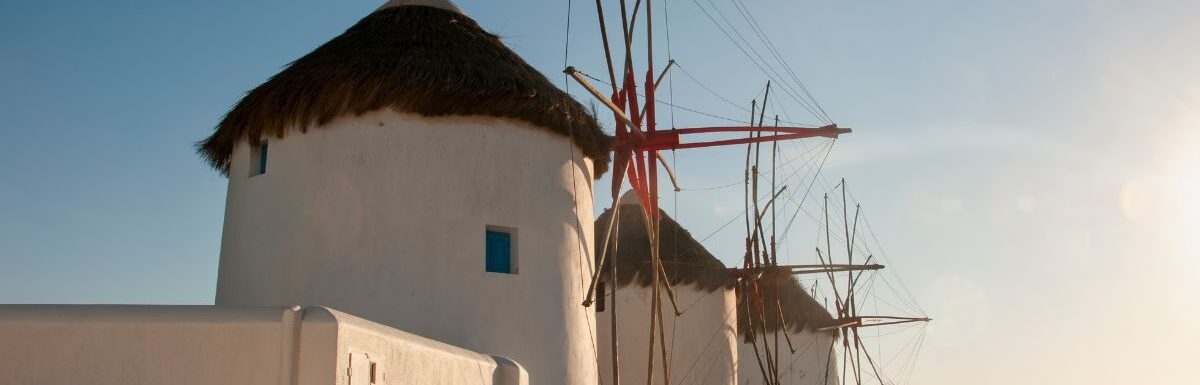Old white windmills and stone walls on the coast of Mykonos island in Greece.