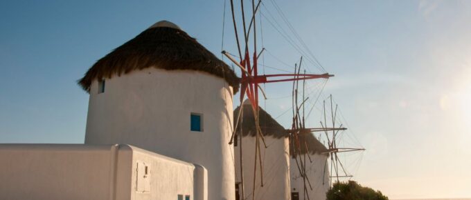 Old white windmills and stone walls on the coast of Mykonos island in Greece.