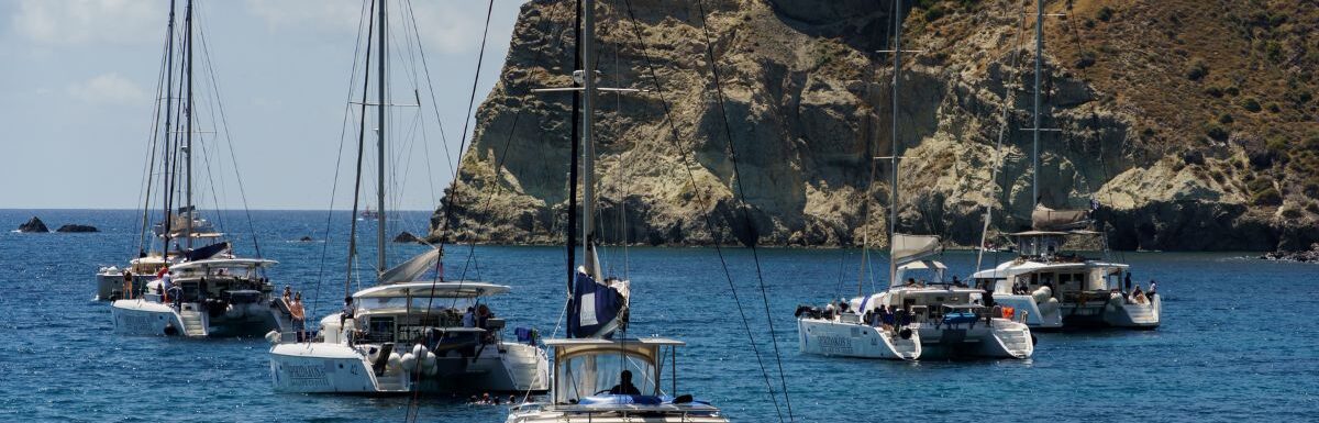 Many yacht sail at the sea near islands. Santorini island, Greece.