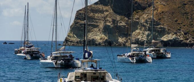Many yacht sail at the sea near islands. Santorini island, Greece.