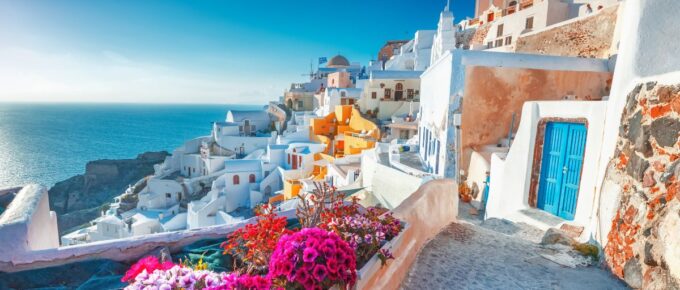 Picturesq view of traditional cycladic Santorini houses on small street with flowers in foreground in Santorini, Greece.