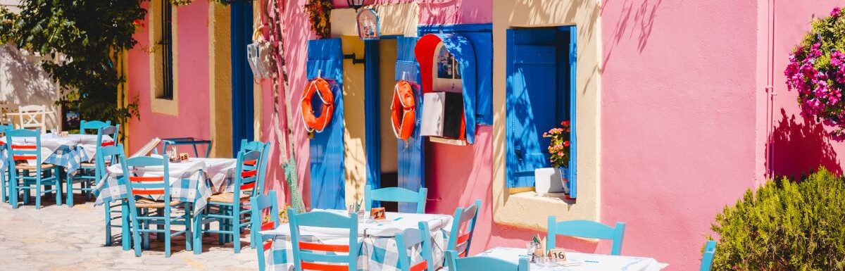 Traditional greek vivid lilac colored tavern on the narrow Mediterranean street on hot summer day.