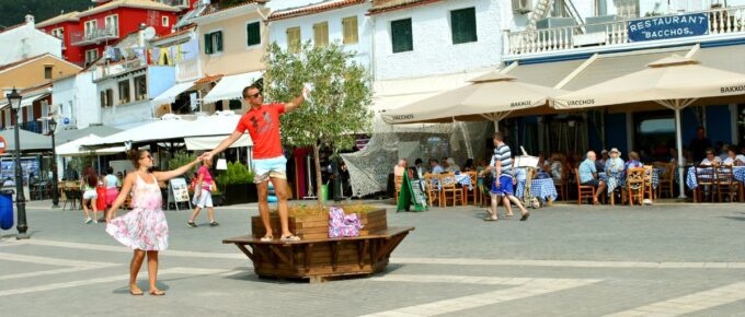 Paxos harbour with a young couple taking a selfie in the town centre while visiting the small island south of Corfu a Greek island in the Ionian sea.