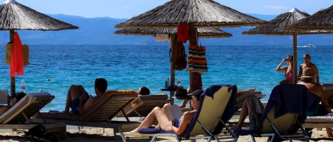 A view on a sand beach with straw parasols on a very warm and sunny summer day in Skiathos, Greece.