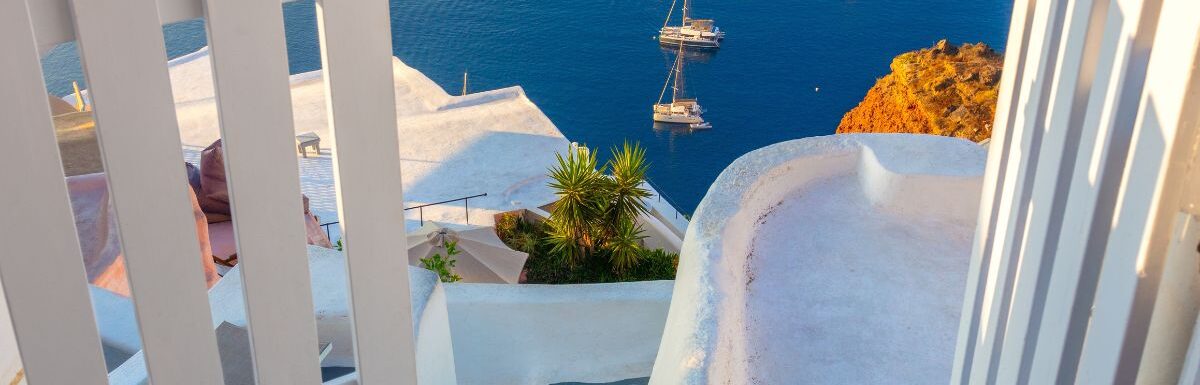 White architecture, open doors, and steps to the blue sea of Santorini in Greece.