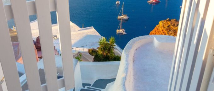 White architecture, open doors, and steps to the blue sea of Santorini in Greece.