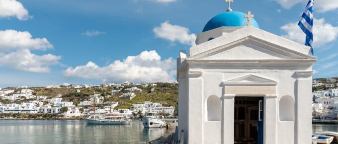 Greek church building and Greek flag in Old Port of Mykonos City, Mykonos, Greece.