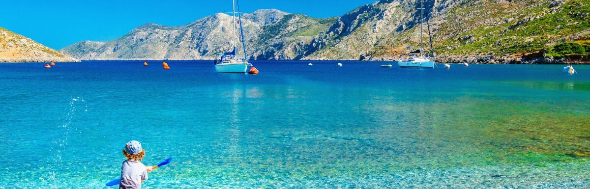 Amazing sea bay on Greek Island with a small boy at play on the seashore, Greece.