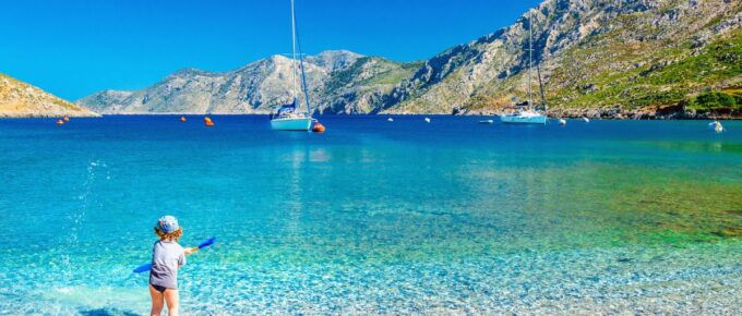 Amazing sea bay on Greek Island with a small boy at play on the seashore, Greece.