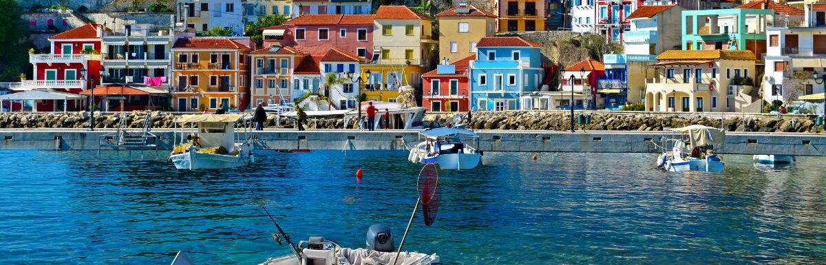 Parga boat on a blue clear water with Greek houses in the background on a sunny day in Greece.