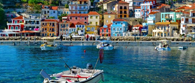 Parga boat on a blue clear water with Greek houses in the background on a sunny day in Greece.