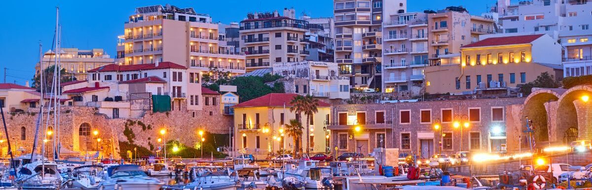 View of Heraklion city with harbour with yachts and fishing boats at dusk, Crete island, Greece.