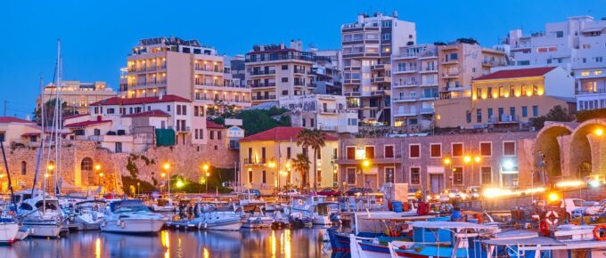 View of Heraklion city with harbour with yachts and fishing boats at dusk, Crete island, Greece.