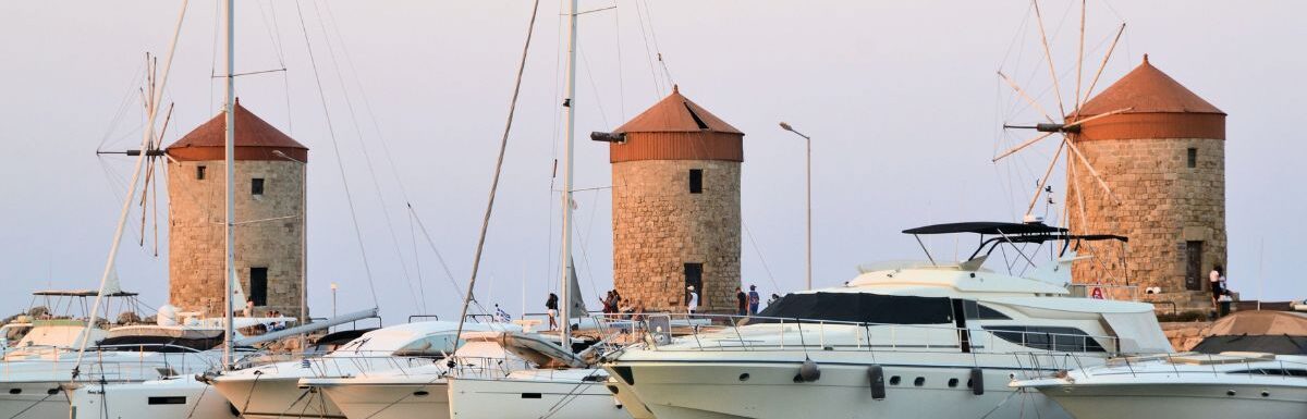 Windmills of Rhodes, Greece with a bunch of boats that are in the water.