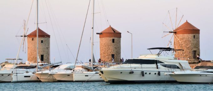 Windmills of Rhodes, Greece with a bunch of boats that are in the water.