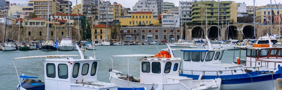 Traditional colorful fishing boats docked at the old Venetian port in Heraklion at sunset in Crete, Greece.