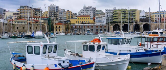 Traditional colorful fishing boats docked at the old Venetian port in Heraklion at sunset in Crete, Greece.