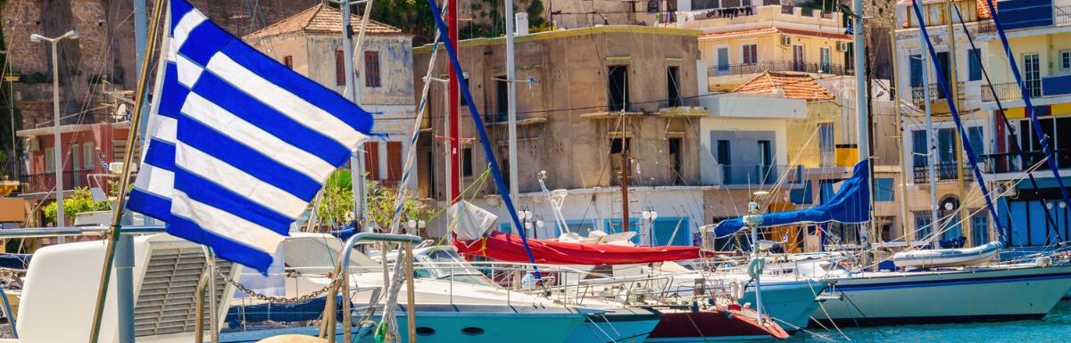 Blue white Greek flag and wind in Greek port full of boats, Kos, Greece.