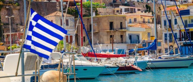 Blue white Greek flag and wind in Greek port full of boats, Kos, Greece.