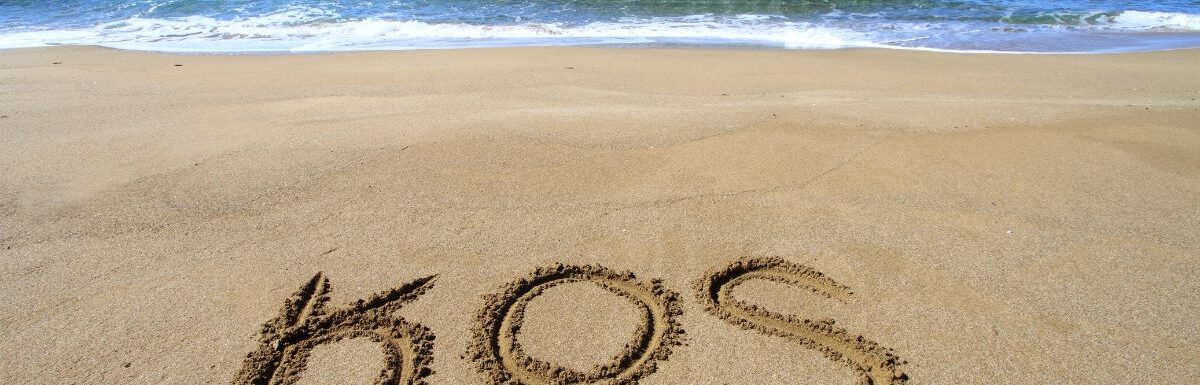 Kos word written on sandy beach.